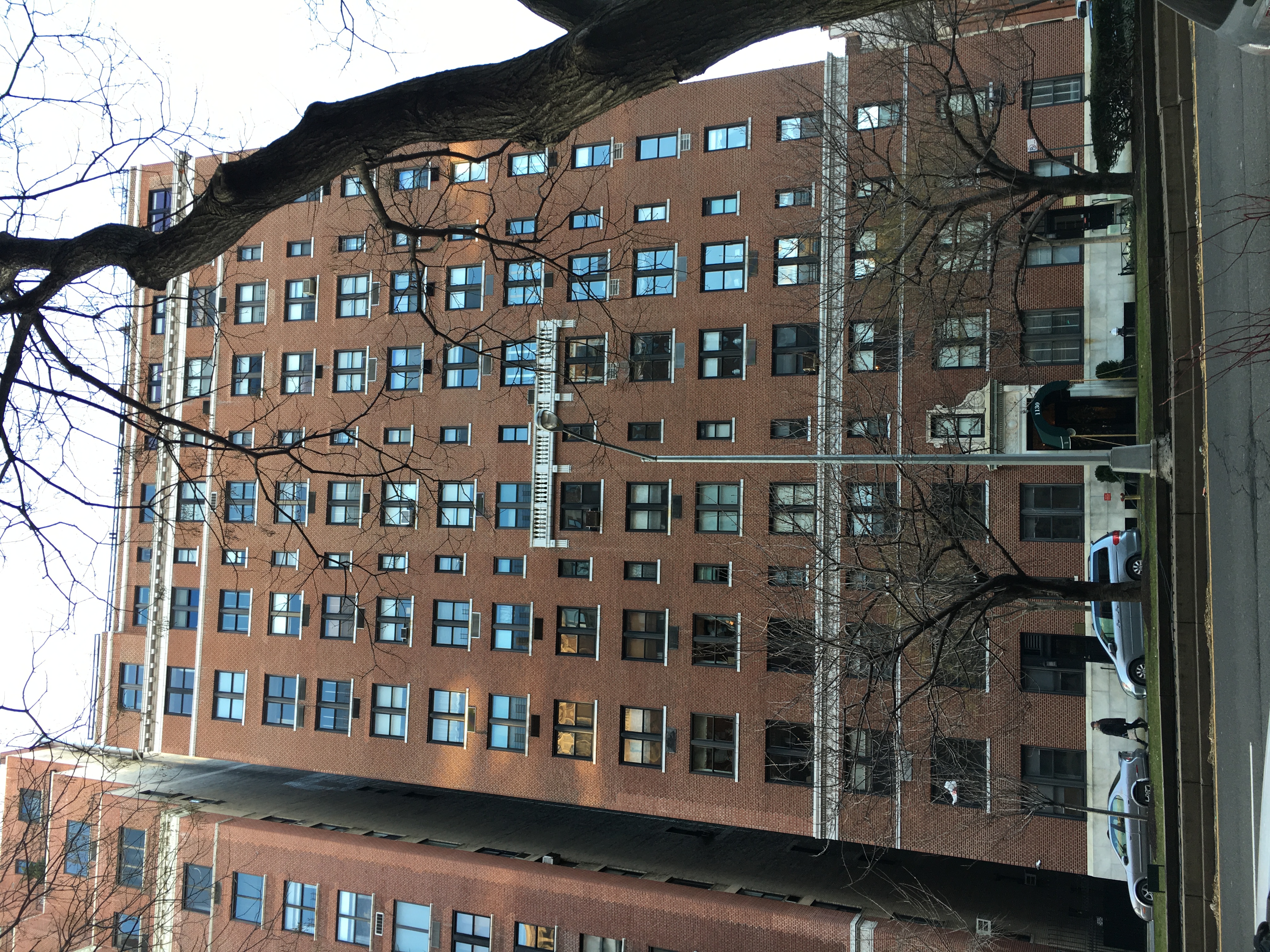 Street-level view of 1130 Park Avenue: red brick, paired windows, limestone entrance and green canopy