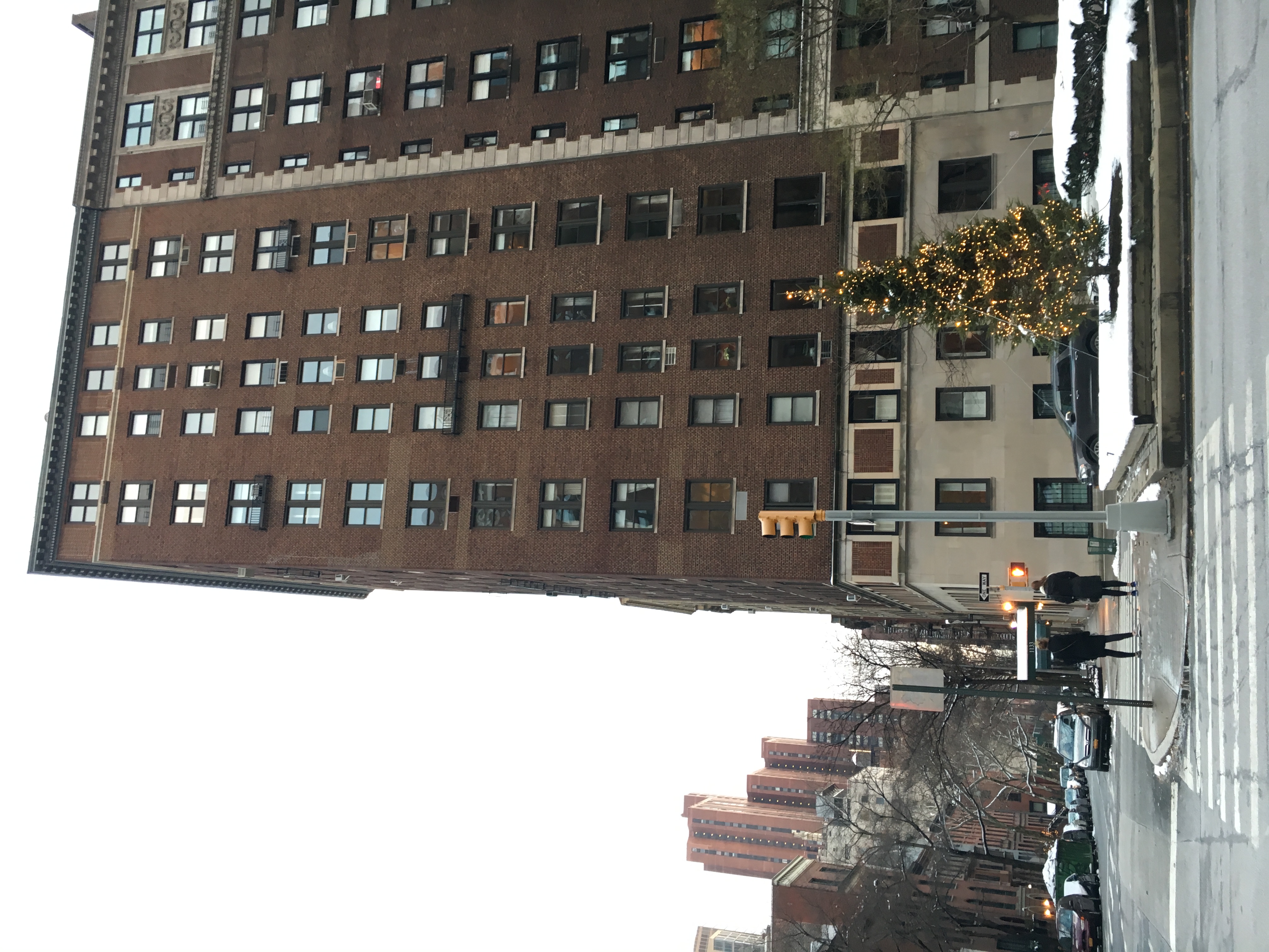 Street-level view of 1133 Park Avenue: dark brick, pale two-story base, iron balconies and stone corner details